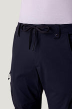Close-up of a person wearing 686 Men's Anything Cargo Pant - Slim Fit by 686, featuring a drawstring waist and adventure-ready 13-pocket details at the waist and sides with a light-colored shirt tucked in.