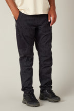 The lower half of a person wearing 686 Men's Anything Cargo Pant - Slim Fit in black, paired with a cream t-shirt and black sneakers, stands against a plain background, showcasing 686 adventure-ready style.