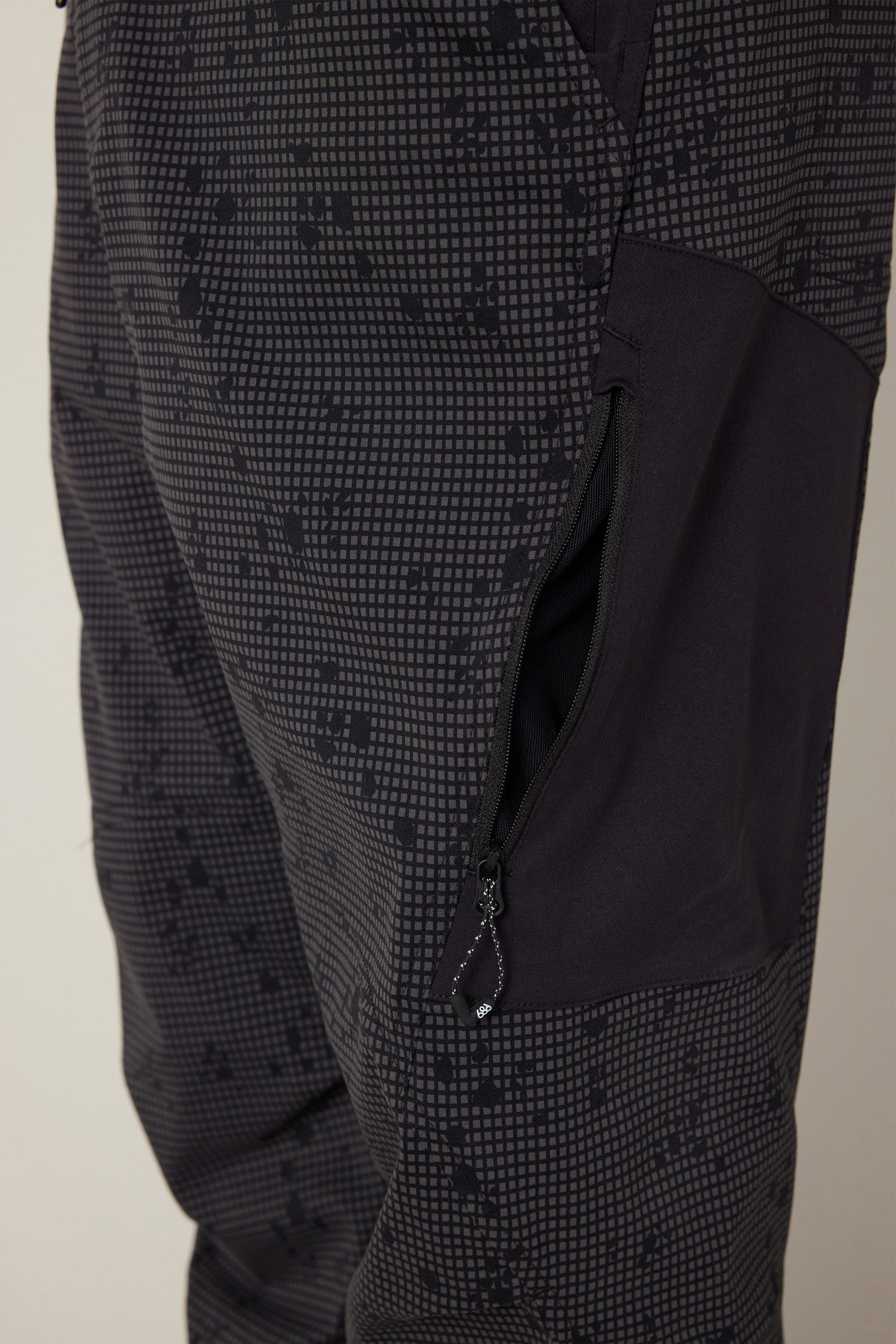 Close-up of the 686 Men's Anything Cargo Pant - Slim Fit, featuring a dark patterned design, visible zippered pocket with black interior—engineered by 686 for adventure-ready style and versatile practicality.