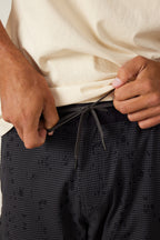 A person tightens the black drawstring on the waistband of their 686 Men's Anything Cargo Pant - Slim Fit while wearing a light beige t-shirt, highlighting the adventure-ready 13-pocket design from 686.
