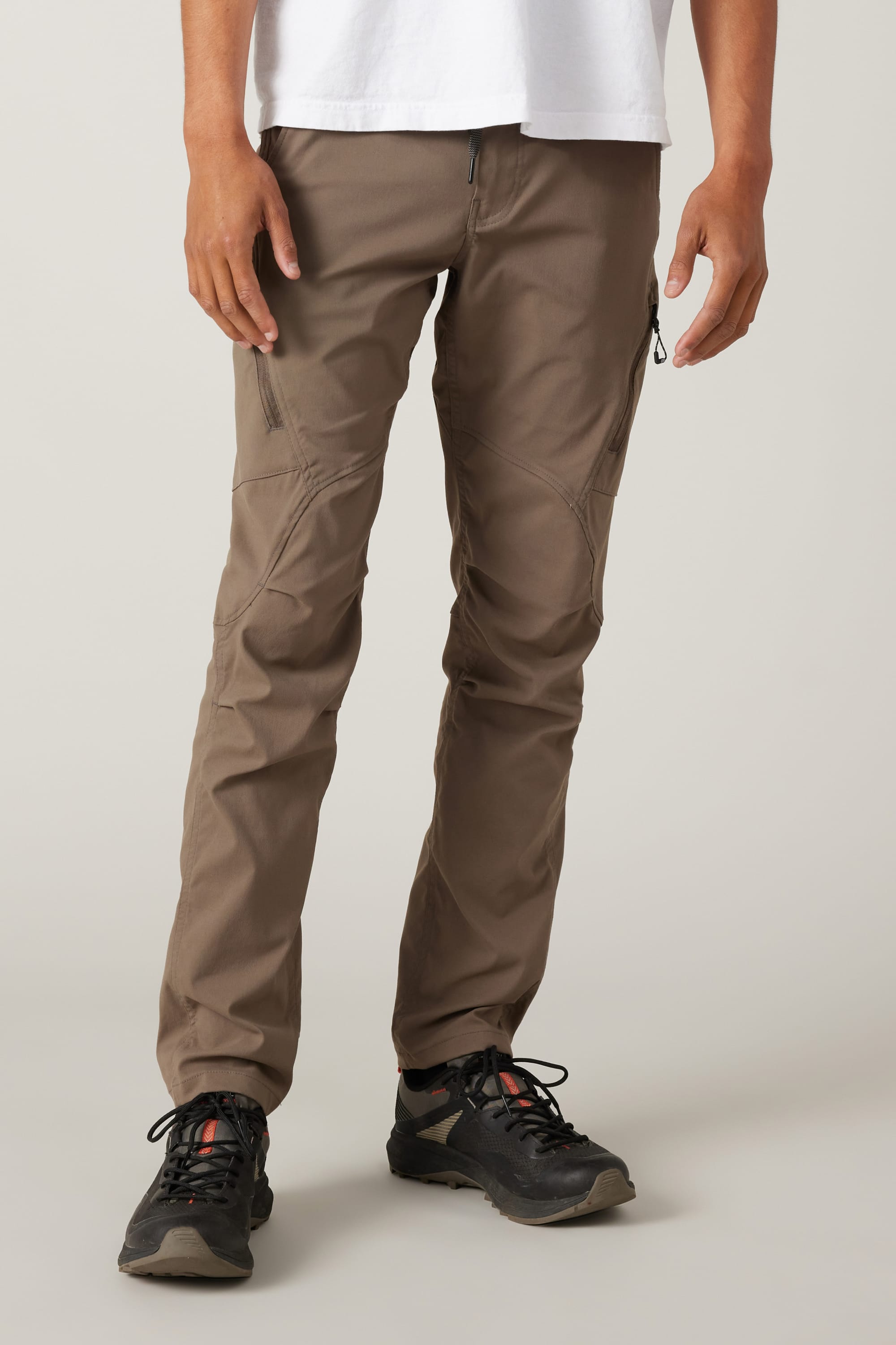 A person in a white t-shirt, 686 Men's Anything Cargo Pant - Slim Fit, and black athletic shoes stands against a plain light background. Only the lower half is visible, showcasing 686's technical style ready for adventure.