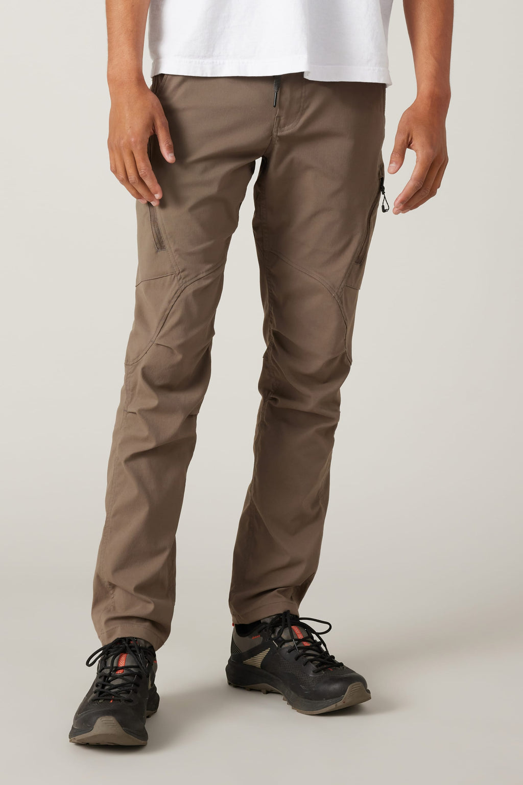 A person wears 686 Men's Anything Cargo Pant - Slim Fit by 686 with zipper pockets and black trail shoes, shown from the waist down against a light background, ready for any adventure.