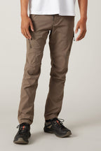 A person wears 686 Men's Anything Cargo Pant - Slim Fit by 686 with zipper pockets and black trail shoes, shown from the waist down against a light background, ready for any adventure.