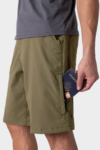 Wearing 686 Men's Everywhere® Hybrid Short - Relaxed Fit and a gray shirt, a person slips a navy blue passport and boarding pass into the shorts' zippered side pocket.
