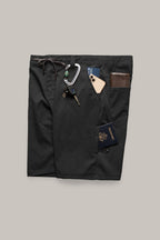 The 686 Men's Everywhere® Hybrid Short – Relaxed Fit, in black, is stain-resistant and features multiple pockets shown holding a smartphone, leather wallet, keys with carabiner, pen, blue card, and U.S. passport on a neutral background.