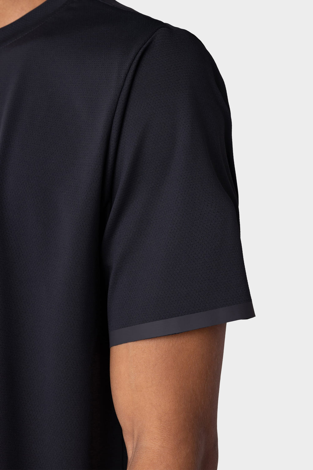 A close-up of a person wearing the 686 Men's Let's Go Tech Tee, a lightweight short-sleeve shirt by 686. Only the upper torso and arm are shown against a plain light backdrop, ideal for spring and summer adventures.