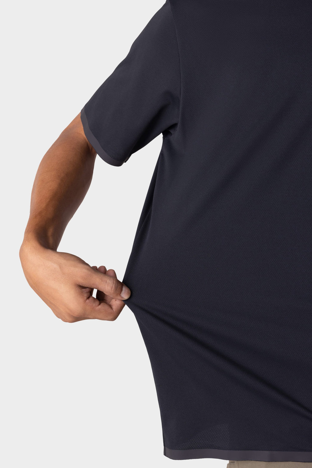 A man stretches the side of the 686 Men's Let's Go Tech Tee—by 686—outward with one hand. The lightweight tech shirt stands out against a plain light background.