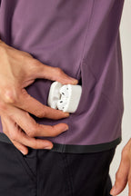 Wearing the 686 Men's Let's Go Tech Tee, a person slides a white wireless earbud case into their pocket, ready for spring and summer adventures.