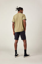 A man faces away from the camera in a 686 Men's Let's Go Tech Tee, black shorts, socks, and high-top sneakers against a plain light background—ideal for spring and summer adventures.
