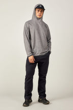 A person stands facing forward in the 686 Mens Lets Go Tech Hoody by 686—a lightweight, breathable top with a subtle pattern—paired with dark pants, black sneakers, and a gray cap, offering comfortable sun protection against a plain background.