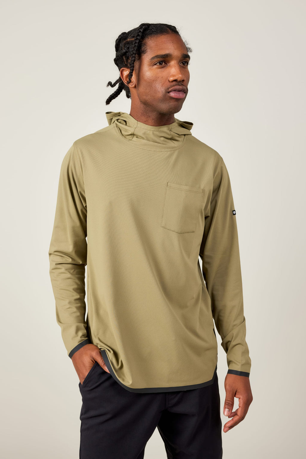 A man with braided hair wears the 686 Mens Lets Go Tech Hoody in light olive green, featuring a chest pocket, standing against a plain light background with one hand in his pocket.
