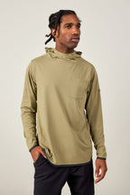 A man with braided hair wears the 686 Mens Lets Go Tech Hoody in light olive green, featuring a chest pocket, standing against a plain light background with one hand in his pocket.