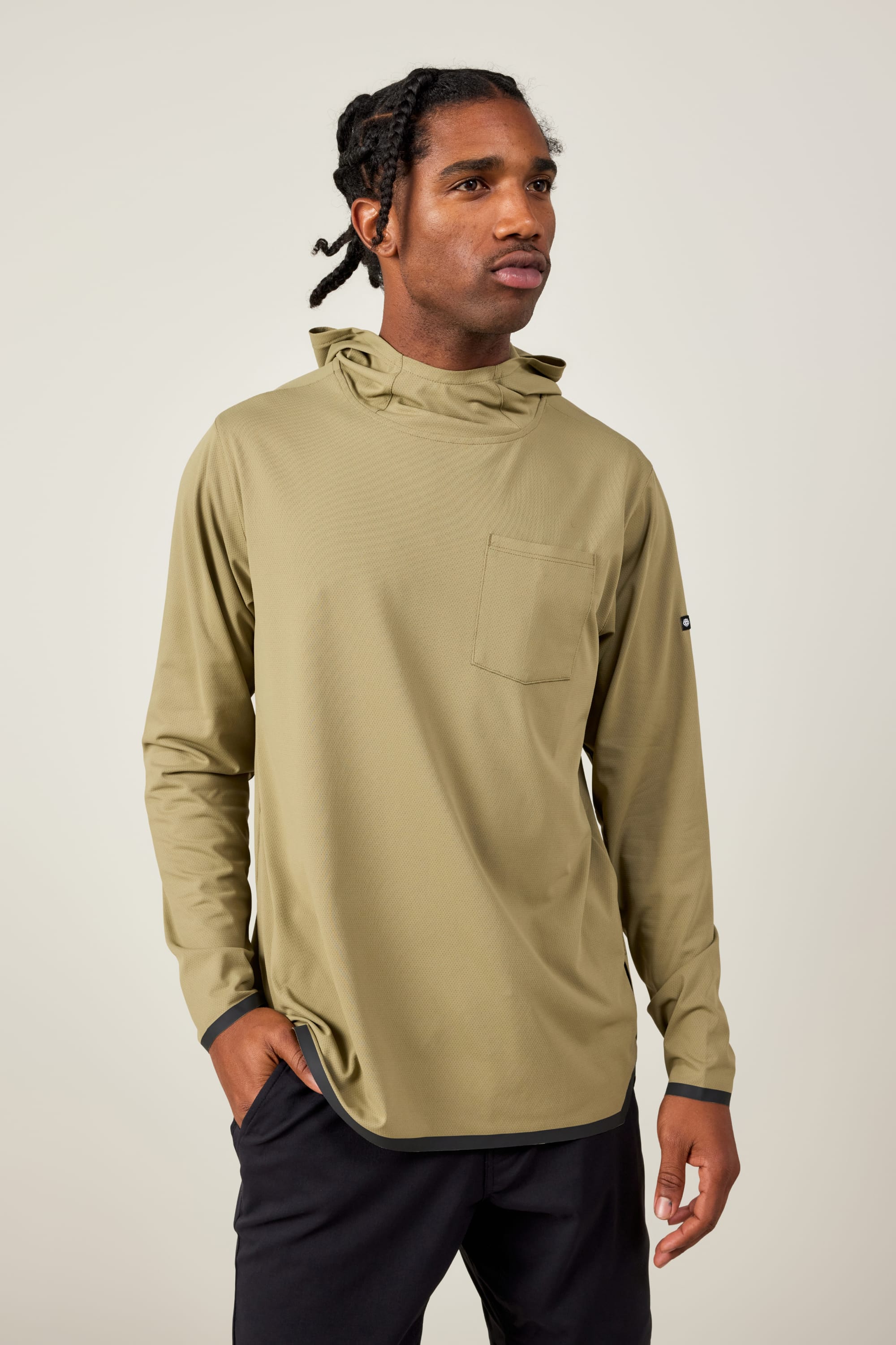 A man with braided hair wears the 686 Mens Lets Go Tech Hoody in light olive green, featuring a chest pocket, standing against a plain light background with one hand in his pocket.