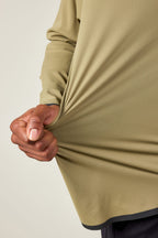 A person stretches the side of their 686 Mens Lets Go Tech Hoody to show the light olive green fabric’s flexibility.