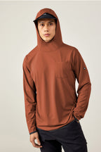 A person in the 686 Men's Let's Go Tech Hoody in rust and a black cap stands against a plain light background.