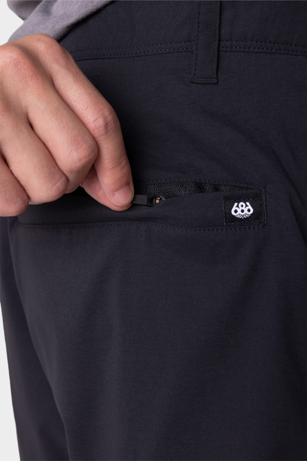 A person's hand slipping a pocket on the 686 Everywhere® Featherlight Chino Short by 686.