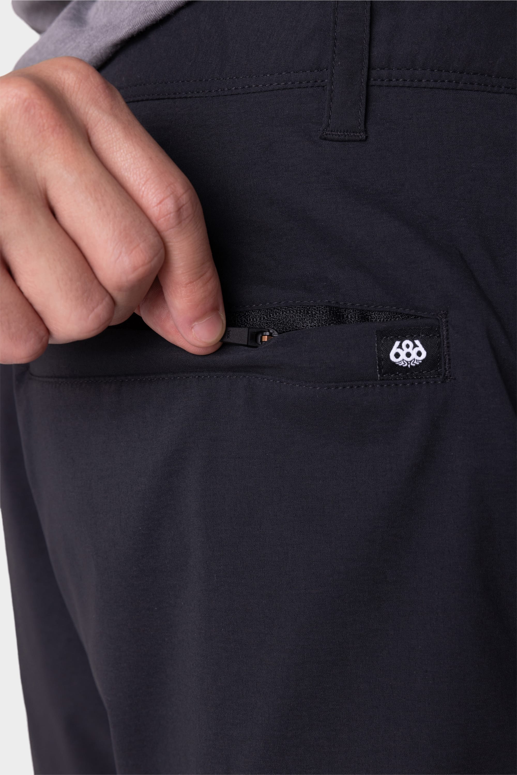 A person's hand slipping a pocket on the 686 Everywhere® Featherlight Chino Short by 686.