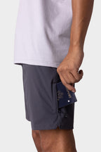 Wearing 686 Men's Everywhere® Featherlight Chino Short, a person slips a navy blue passport into the side pocket of their shorts.