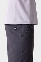 A side view shows a person wearing a light gray T-shirt and 686 Men's Everywhere® Featherlight Chino Shorts in dark gray, with a visible black and white 686 brand tag above the pocket. The background is plain and light-colored.