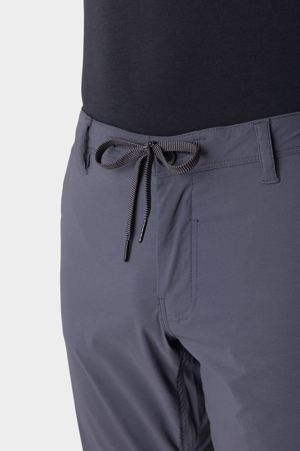 Close-up of a person wearing 686 Men's Everywhere® Featherlight Chino Pant - Slim Fit in gray with belt loops and a tied drawstring, paired with a black top—these lightweight pants from 686 are perfect for any summer wardrobe.
