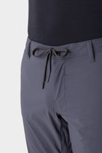 Close-up of a person wearing 686 Men's Everywhere® Featherlight Chino Pant - Slim Fit in gray with belt loops and a tied drawstring, paired with a black top—these lightweight pants from 686 are perfect for any summer wardrobe.