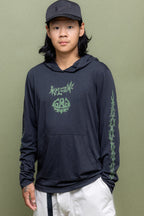 A man wears the 686 Mens Everywhere drirelease® Long Sleeve Hooded Tech Tee, paired with a black cap and light-colored pants. He stands against an olive green backdrop and looks at the camera with a neutral expression.