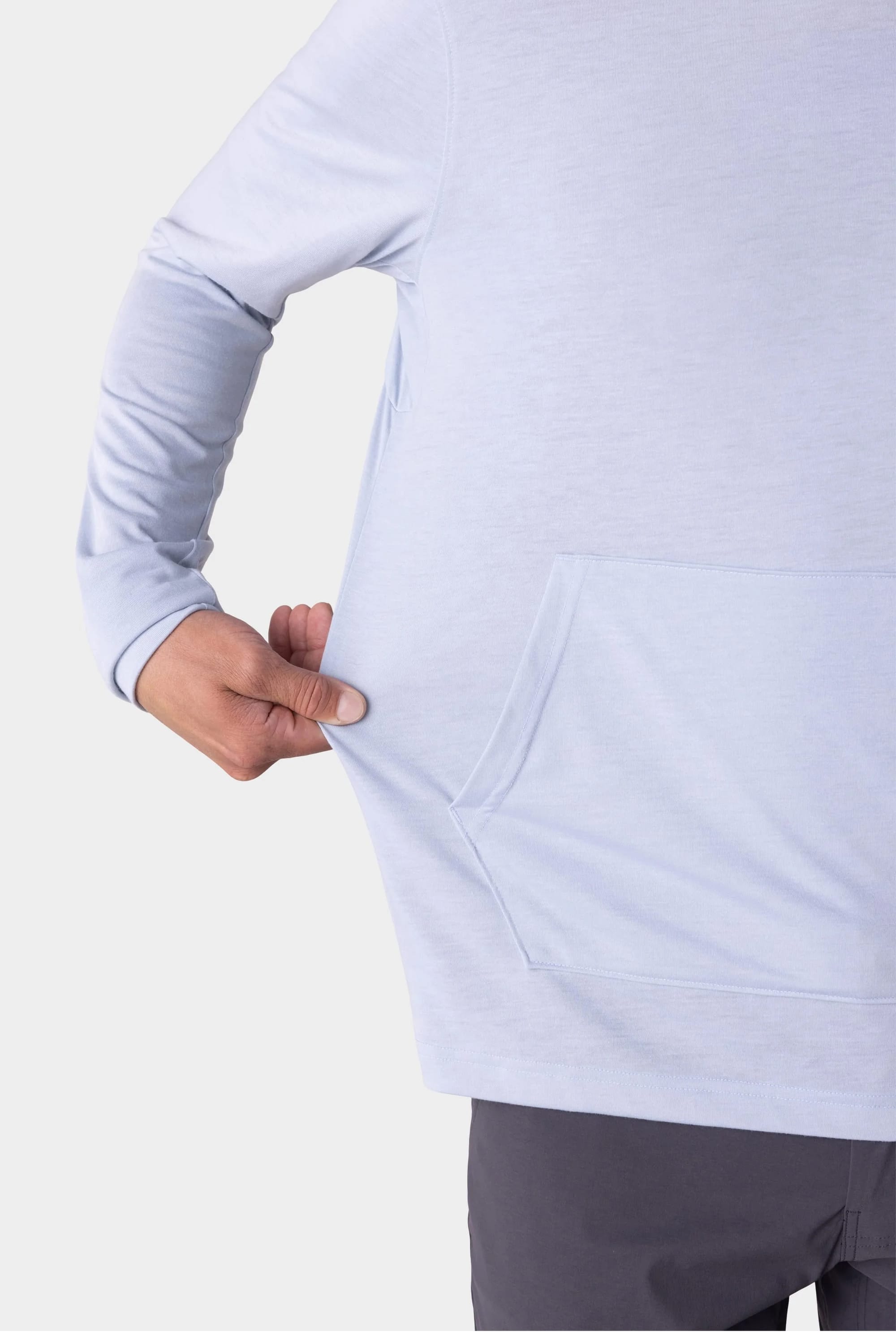 A man wearing the 686 Mens Everywhere drirelease® Long Sleeve Hooded Tech Tee in light blue tugs at his shirts side near the front pocket, showing off its stretch.