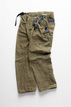 The 686 Cruiser Pant - Wide Fit by 686 in olive green is shown laid flat with a black belt, keychain, and blue carabiner at the waist, plus a black smartphone peeking out of the front pocket, all on a white background.