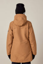 A person wearing the 686 Womens Spirit Insulated Jacket, a black beanie, gloves, and dark pants stands with their back to the camera against a plain light background.