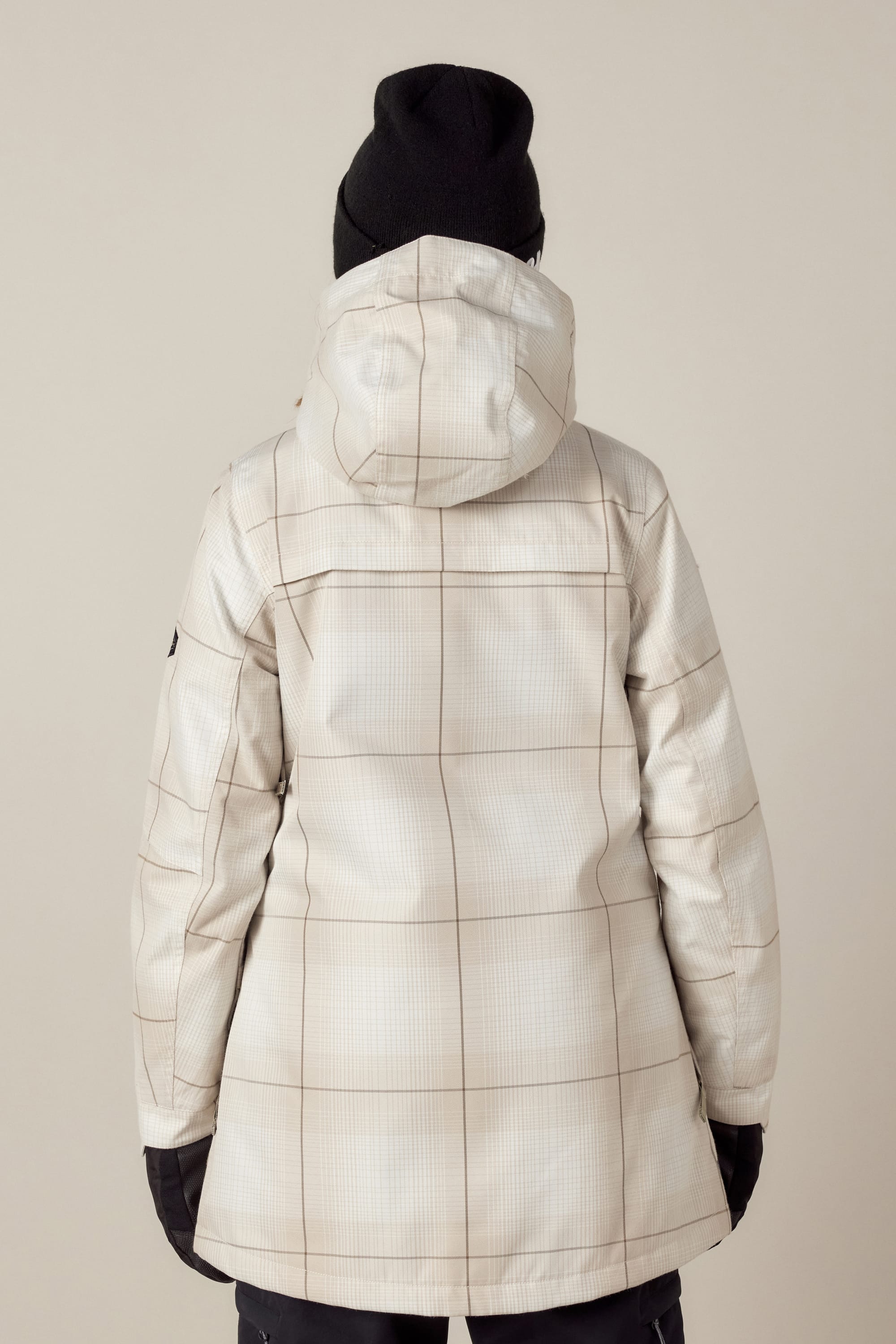 A person is shown from the back against a plain background wearing the 686 Womens Spirit Insulated Jacket with a subtle plaid pattern, paired with black gloves and a black beanie.