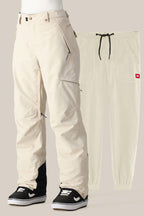 The 686 Women's SMARTY® 3-in-1 Cargo Pant by 686 is shown in cream with black ankle cuffs, zippered pockets, and a removable liner, styled over black-and-white sneakers and paired with matching cream jogger pants for versatile wear.