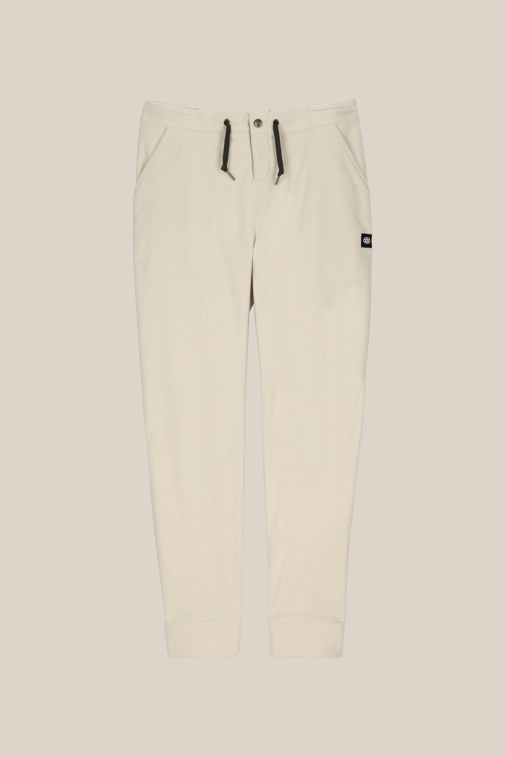 The 686 Women's SMARTY® 3-in-1 Cargo Pant features ribbed cuffs, two side pockets, a drawstring waistband with black ties, three ways to wear, and a small black logo tag on the right pocket. Shown against a light beige background.