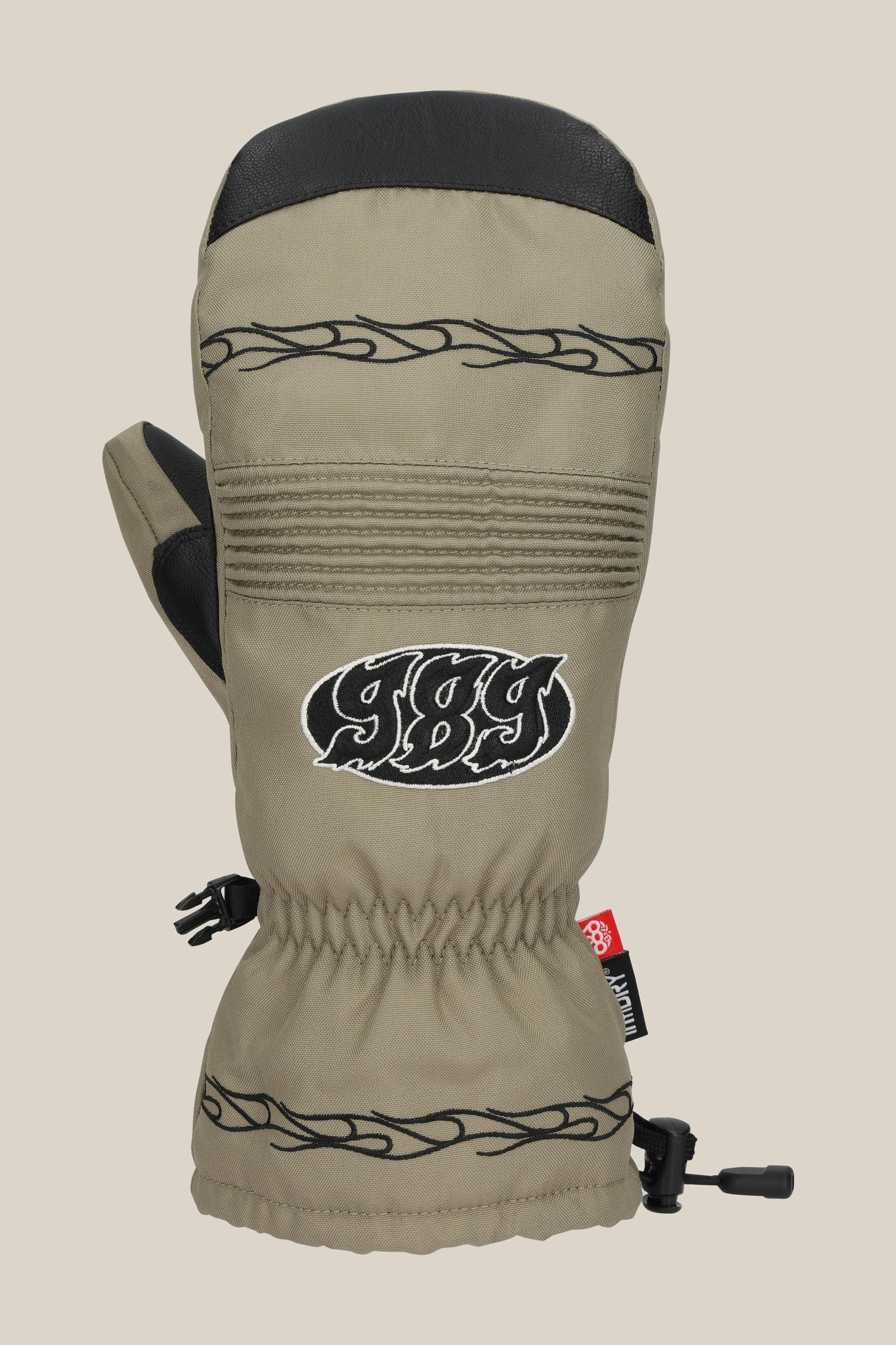 The 686 Lander™ Mitt by 686 is a khaki waterproof mitt with black leather accents, black tribal embroidery, “989” on the front, light insulation, elastic wrist, red tag, adjustable cuff drawstring, and Soundtouch technology.