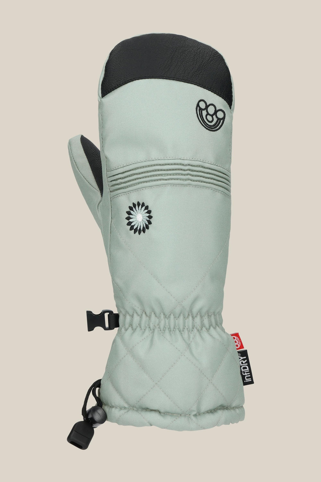 The 686 Women's Jubilee™ Mitt by 686 is a light gray waterproof mitten featuring a black thumb tip and top, flower and smiling face embroidery, elastic wrist, clip, and a red cuff tag. Shown against a beige background.