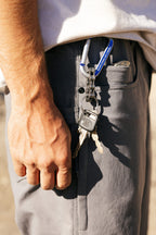 Wearing the 686 Men's Unwork® Pant - Relaxed Loose Fit, a person has keys on a chain clipped to their pocket. Their hand rests at their side as sunlight highlights both the durable pants from 686 and the glinting keys.