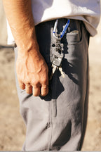 Wearing the 686 Men's Unwork® Pant - Slim Fit, someone with keys on a blue carabiner clipped to their front pocket pairs durability and style, showing off classic 686 workwear in a practical look with a white shirt.