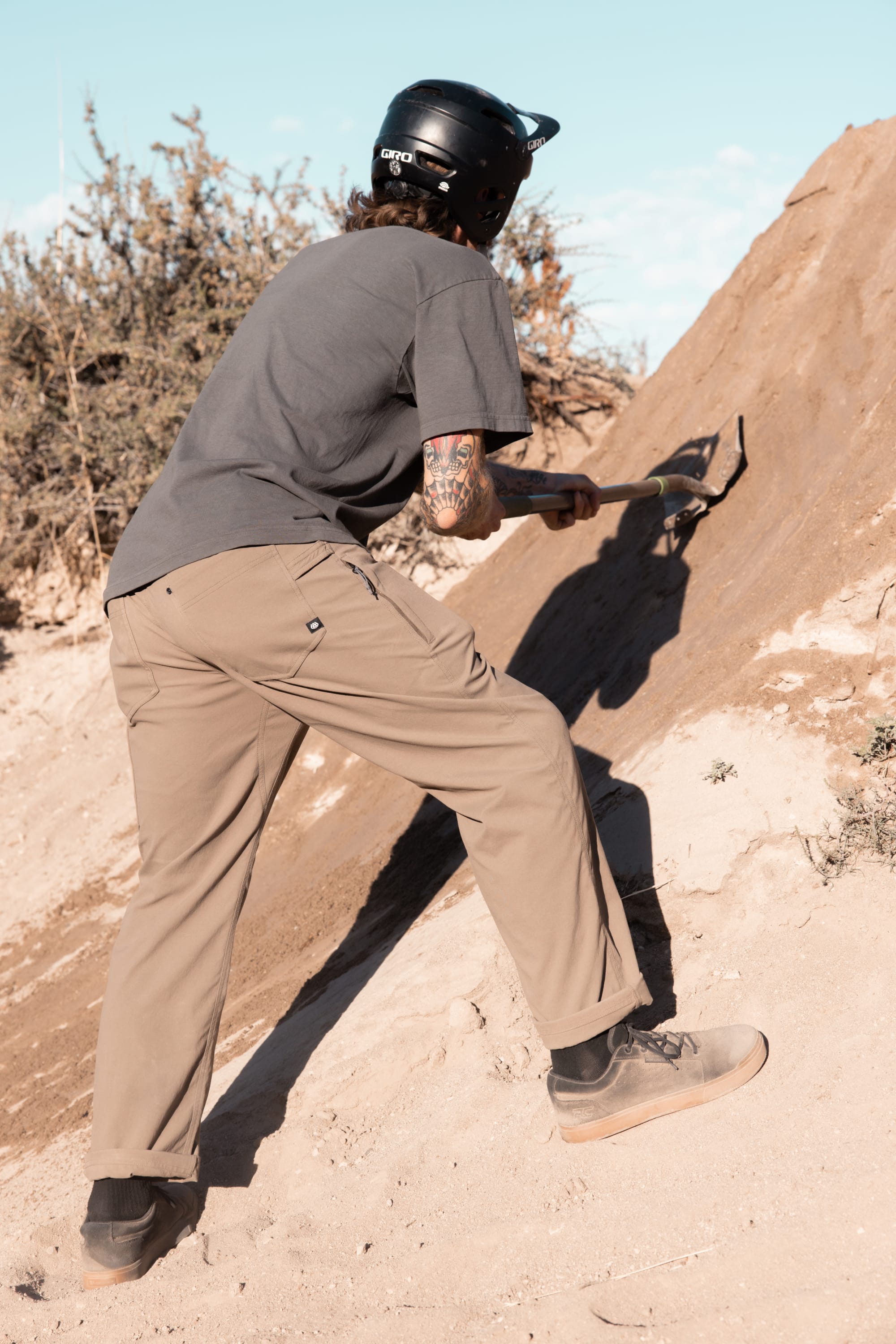 A man with a shovel on a hill, dressed in classic workwear and 686 Men's Unwork® Pant - Slim Fit, ready for any outdoor task.