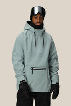 A person wearing the 686 Mens Waterproof Hoody in light gray stands against a plain beige background, paired with black ski goggles, gloves, and pants.
