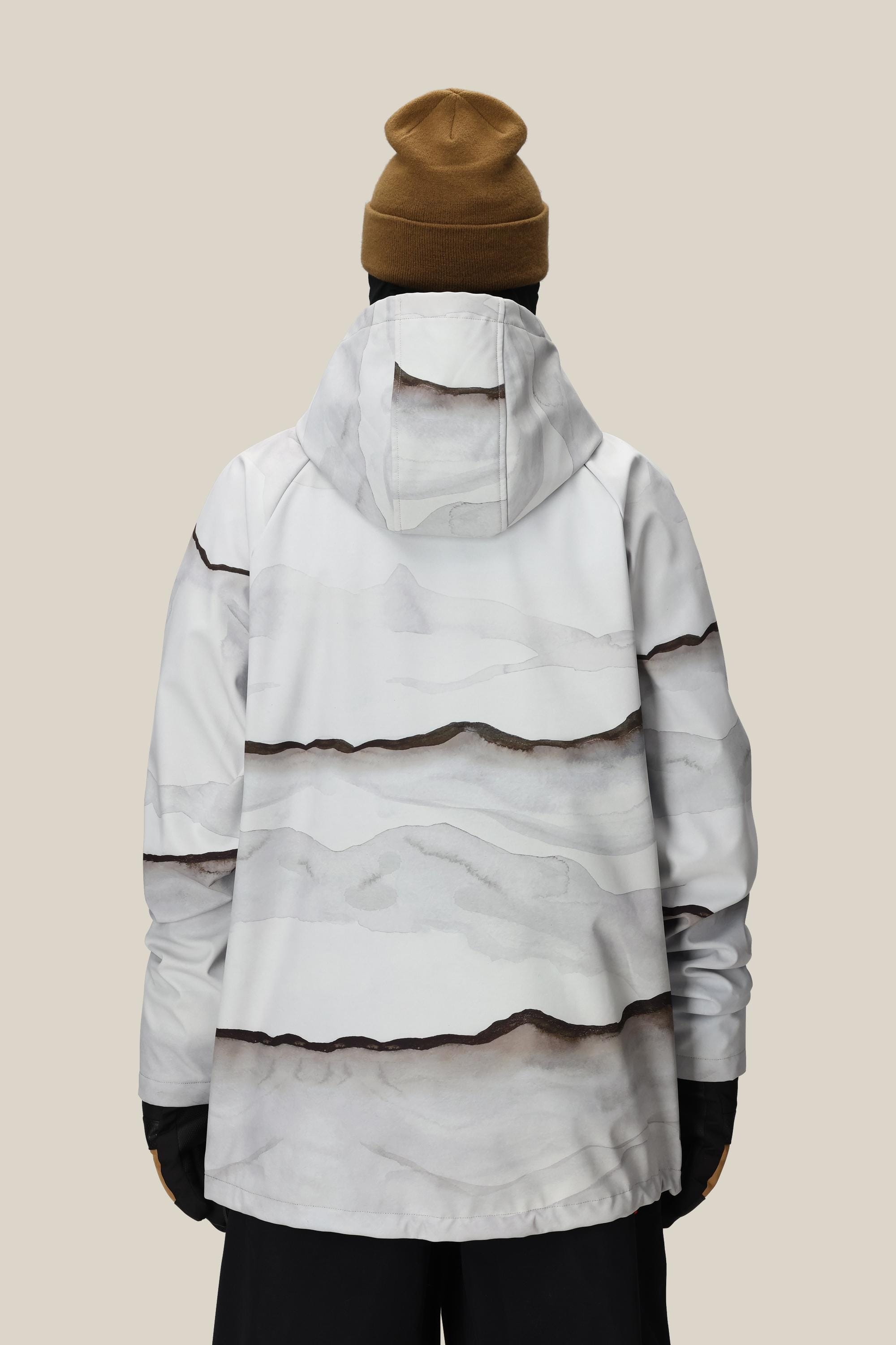 A person wearing the 686 Mens Waterproof Hoody by 686, featuring a fleece lining and white fabric with abstract gray and brown wave patterns, along with a brown beanie and black gloves, stands with their back to the camera against a beige background.