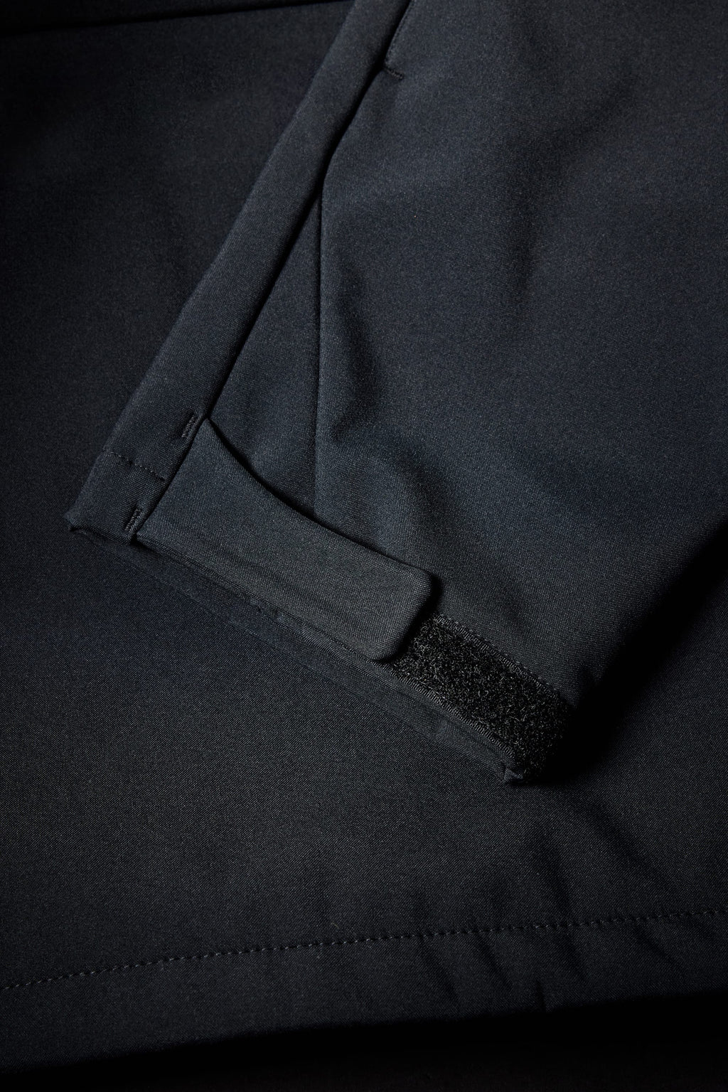 A close-up of the 686 Mens Waterproof Hoody by 686 shows a dark sleeve with a Velcro cuff strap, visible pocket seam, and detailed stitching.