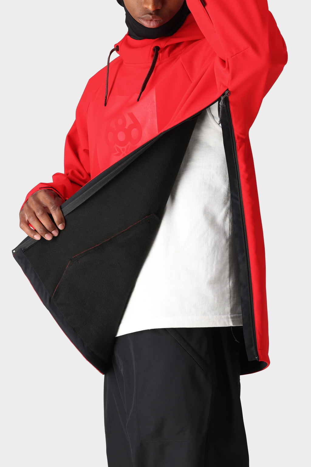 A person wears the 686 Mens Waterproof Hoody in bright red with black drawstrings and lining, side zipper open to show a white t-shirt. The hood partially obscures the face. Brand: 686.