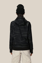 A person wearing a black beanie, light-colored pants, and the 686 Womens Bonded Fleece Pullover Hoody by 686 stands facing away against a plain beige background.