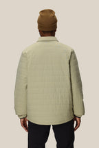 A person wearing the 686 Men's Thermaldry™ Snap-Up Shirt stands facing away, highlighting the back of this stylish 686 citywear against a plain light background.