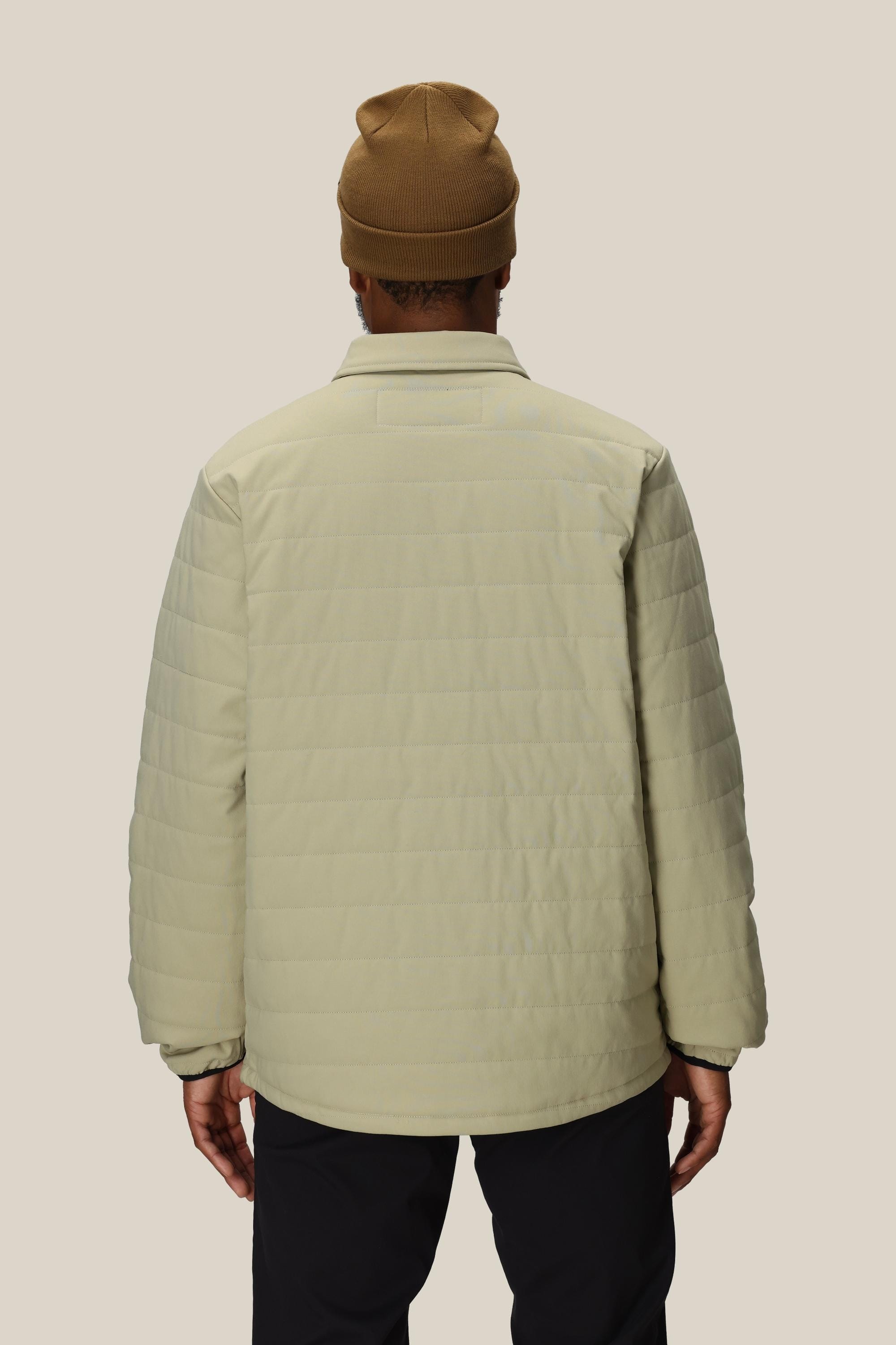 A person wearing the 686 Men's Thermaldry™ Snap-Up Shirt stands facing away, highlighting the back of this stylish 686 citywear against a plain light background.