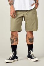 A person wears 686 Men's Everywhere® Ripstop Short - Relaxed Fit in olive green, a white T-shirt, black crew socks, and black high-top Converse. Their tattooed legs and hands rest by their sides against a plain light gray background.