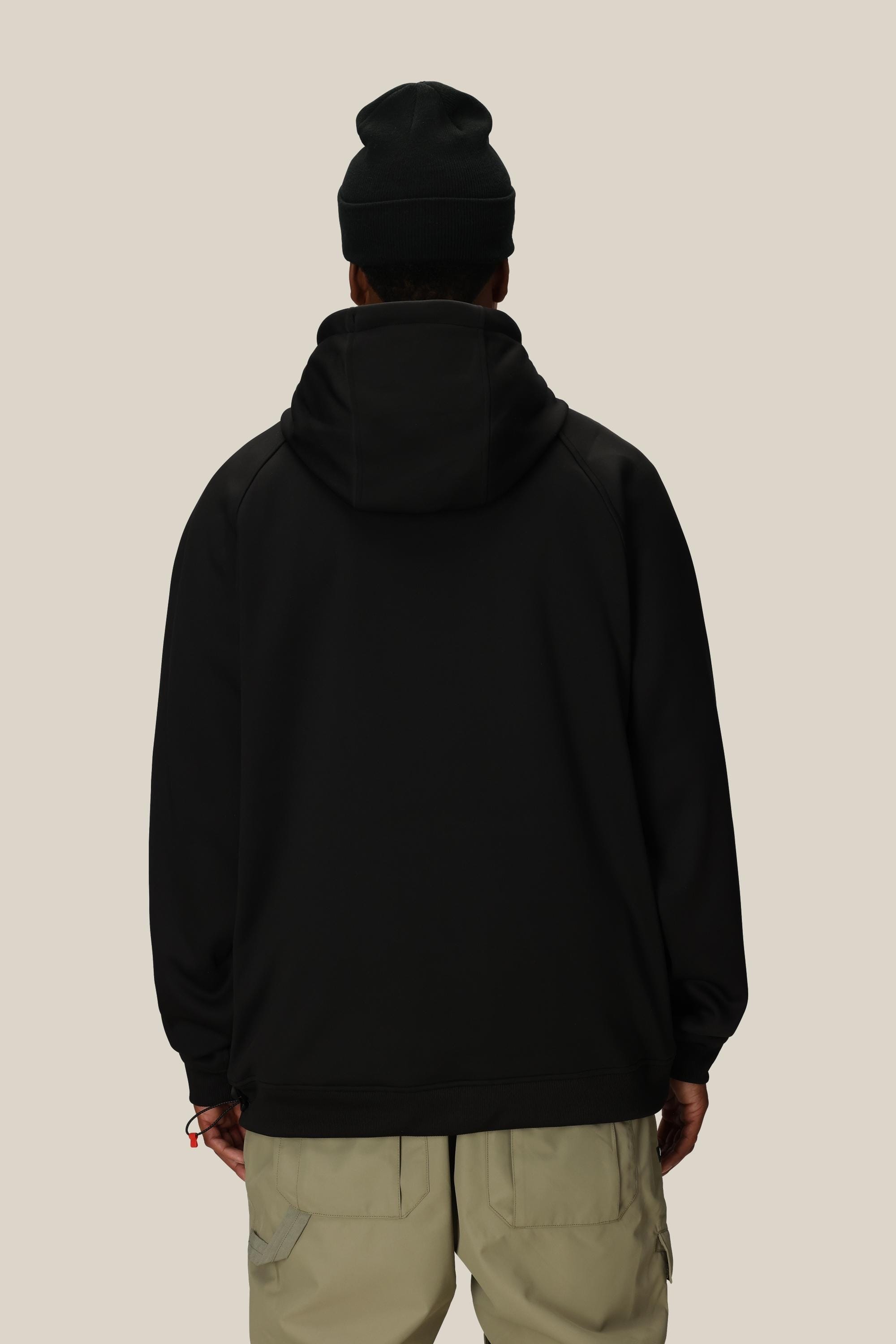 A person faces away, showcasing the back of a 686 Mens Bonded Fleece Pullover Hoody in black and a matching black beanie. They wear light beige pants, all set against a plain, light background.