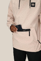 A person wearing the 686 Mens Waterproof Hyperchromic Pullover Hoody is placing a black smartphone into its secure pocket. Only the persons torso and hand are visible.