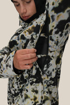 A person wearing the 686 Men's Hydra™ Thermagraph® Jacket unzips a side vent, revealing black mesh body-mapped lining inside. The background is plain and neutral.