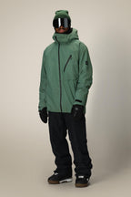 A person wears a 686 Men's Hydra™ Thermagraph® Jacket, black snow pants, black gloves, brown snow boots, a green beanie, and large reflective ski goggles against a plain light background.