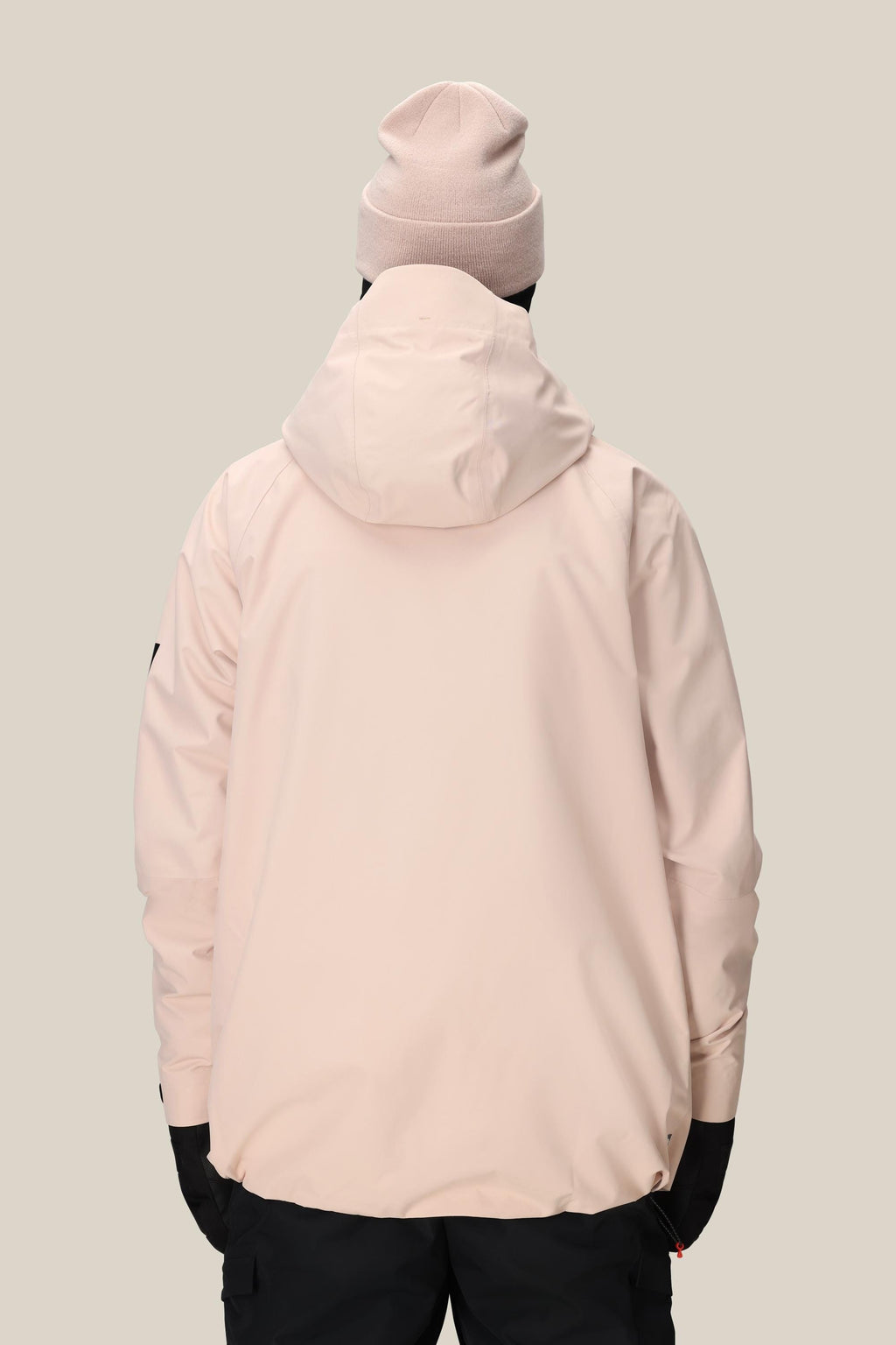 A person wearing the 686 Men's Hydra™ Thermagraph® Jacket in light pink, a matching beanie, and black pants stands with their back to the camera against a plain beige background.